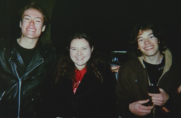 Piromane BTS (2023) Two actors stand with their director between them, all smile widely.