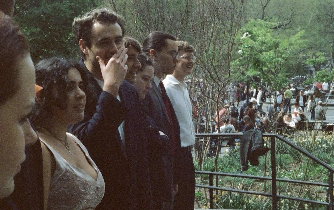 The cast of an outdoor play stands in a line about to bow. Some are very happy, some a little thoughtful.