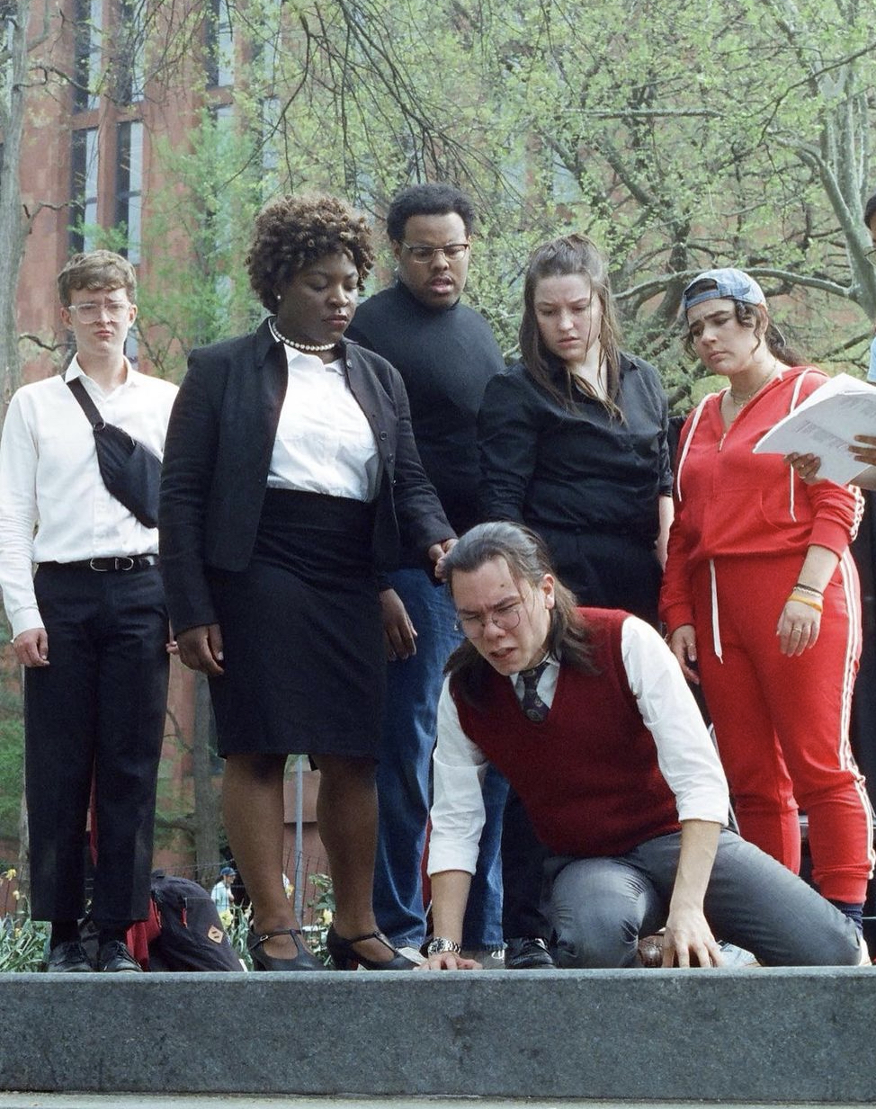 King Lear (2023) At an outdoor theatre, a group of actors rehearses. They huddle around a young man who is on the ground. He has a pained expression, and everyone else looks very concerned