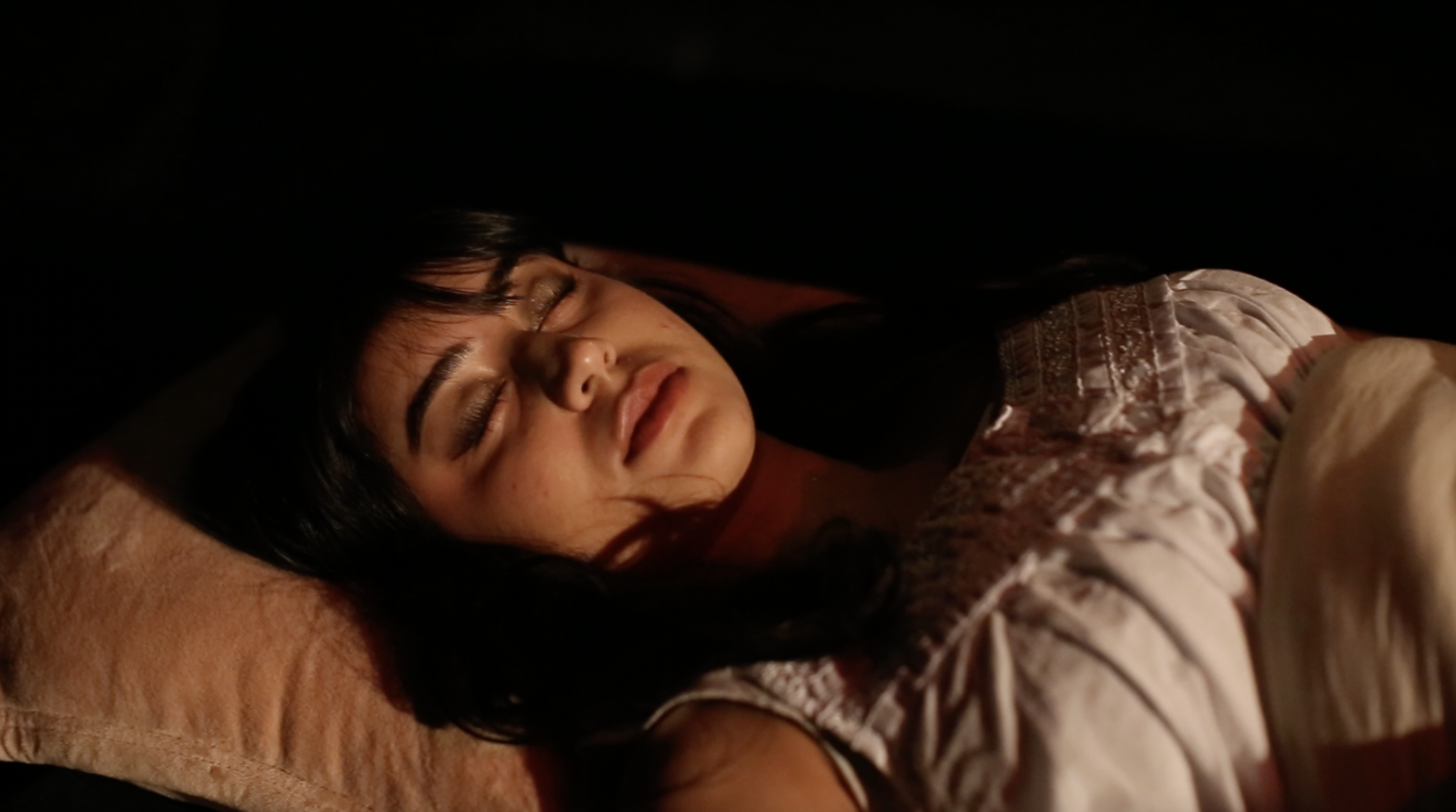 A young woman pretends to sleep on a stage.