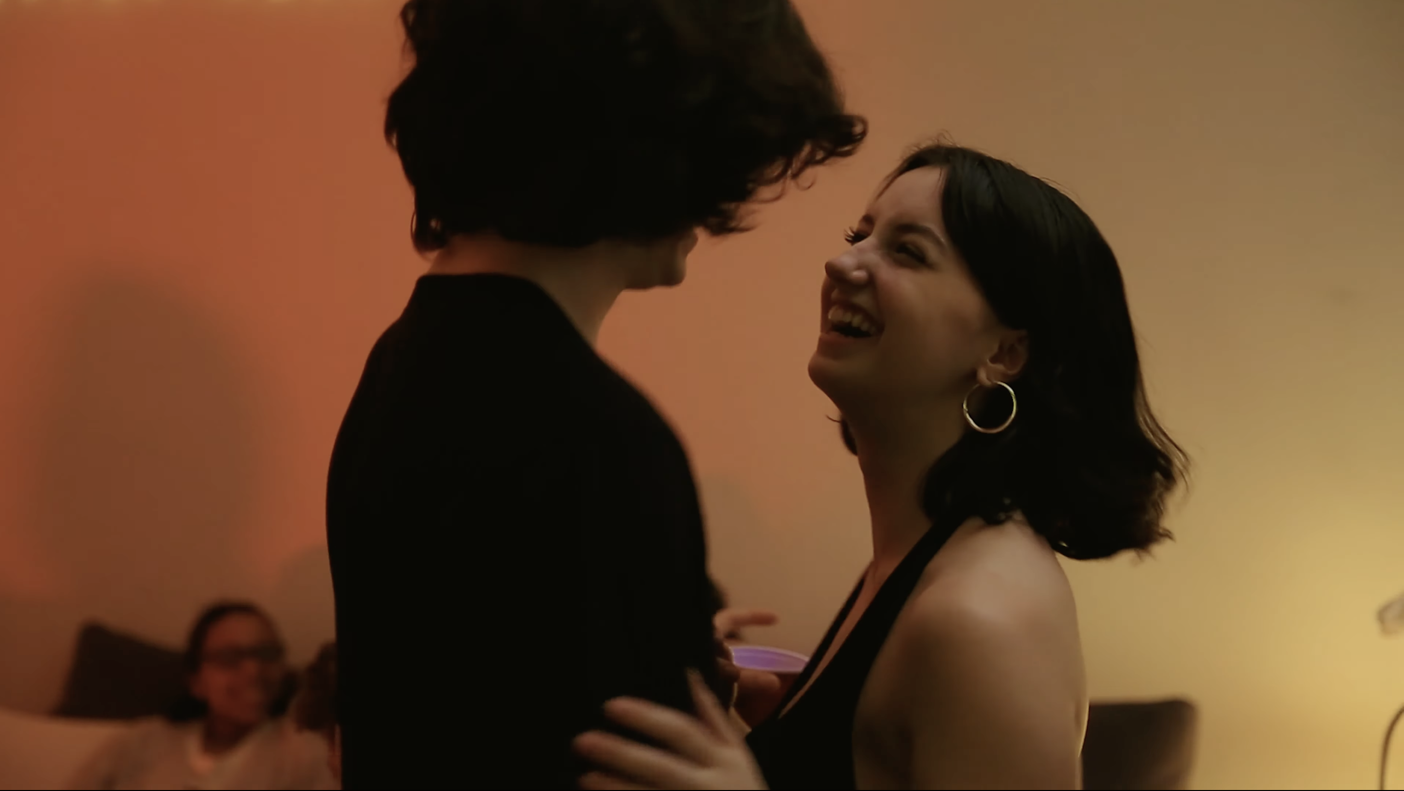 A young man and woman dance at a house party.