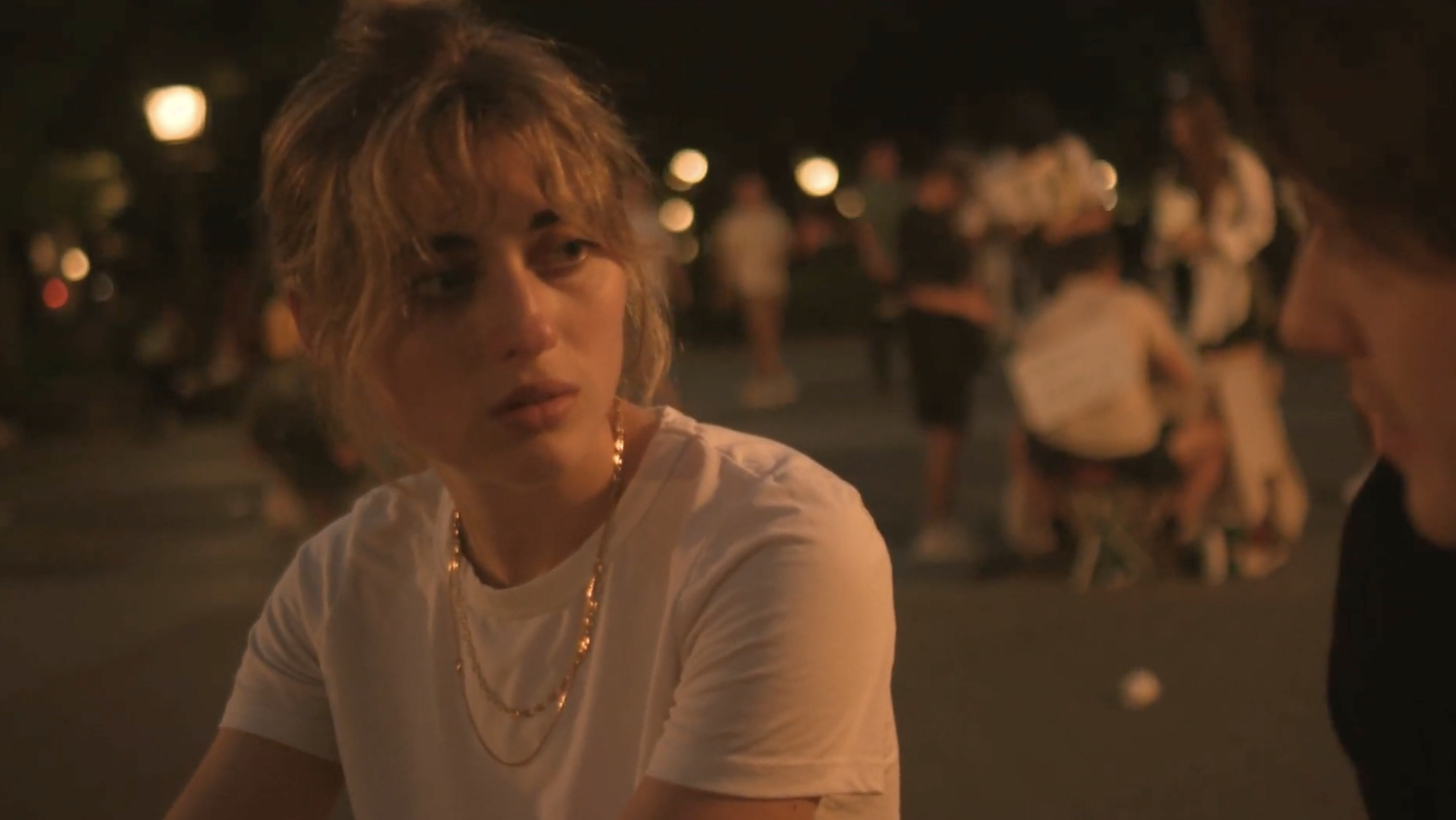 A young woman stares at a young man. She looks thoughtful.