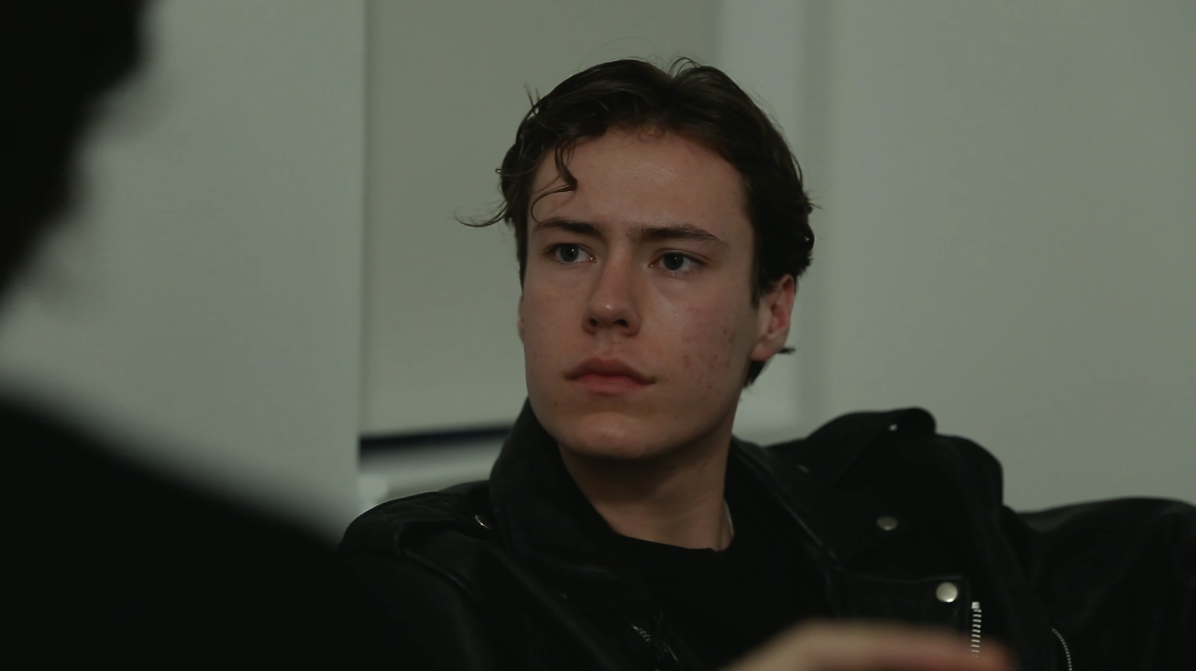 A young man stares concernedly at another.